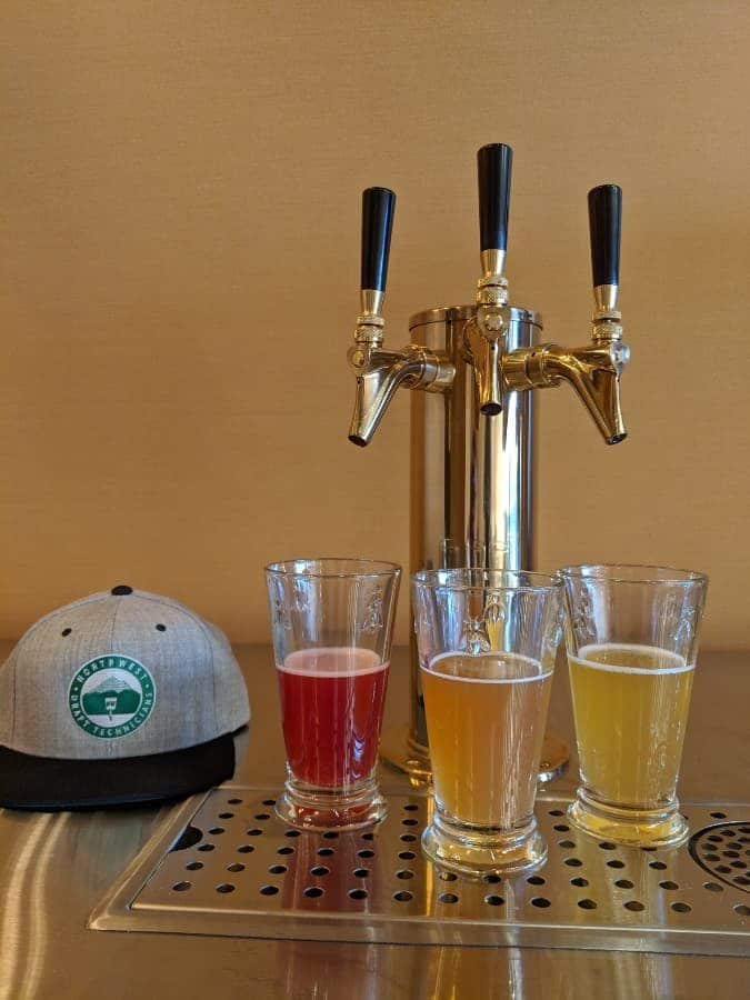 Three glasses of beer sit on a custom Northwest Draft Technicians kegerator with three taps