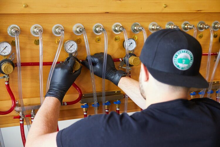 A technician from Northwest Draft Technicians installs a line on a kegerator system