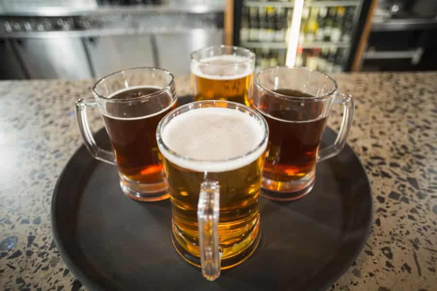 Four glasses of draft beer on a tray