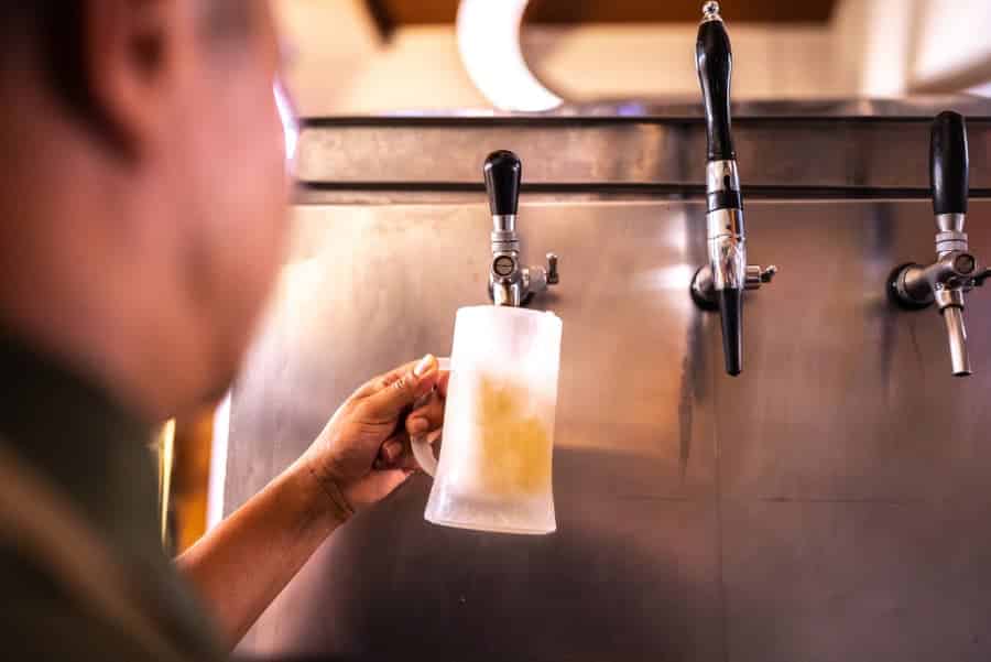 Bartender pouring beer into drinking glass from tap