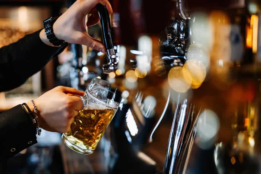 Bartender pouring beer from tap into glass mug