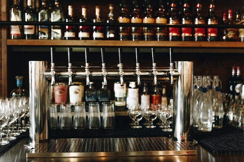 Front view of double column draft system with glasses and alcohol on shelves in background